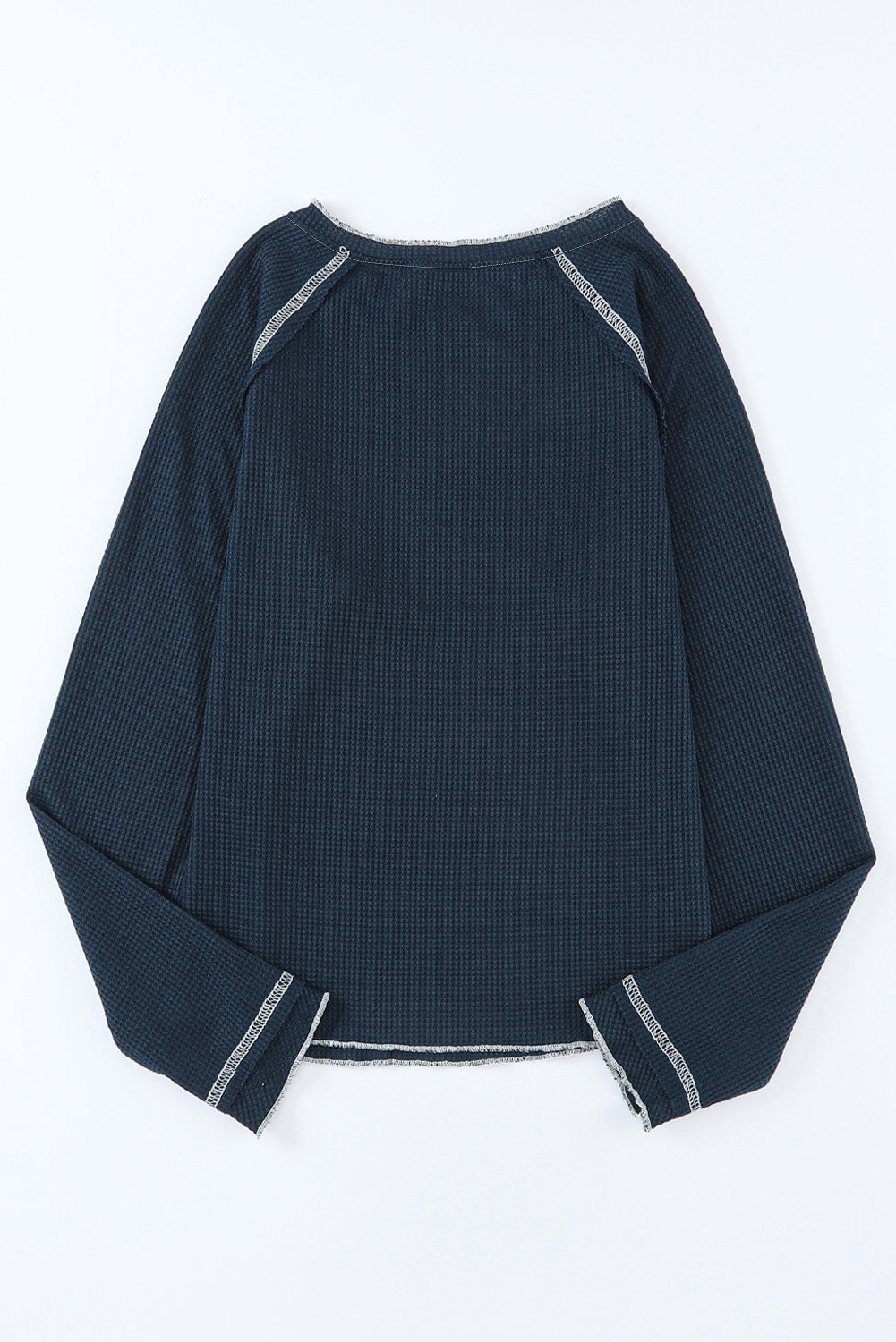 Close-up of navy knit texture and contrast white stitching on open hem sweater.